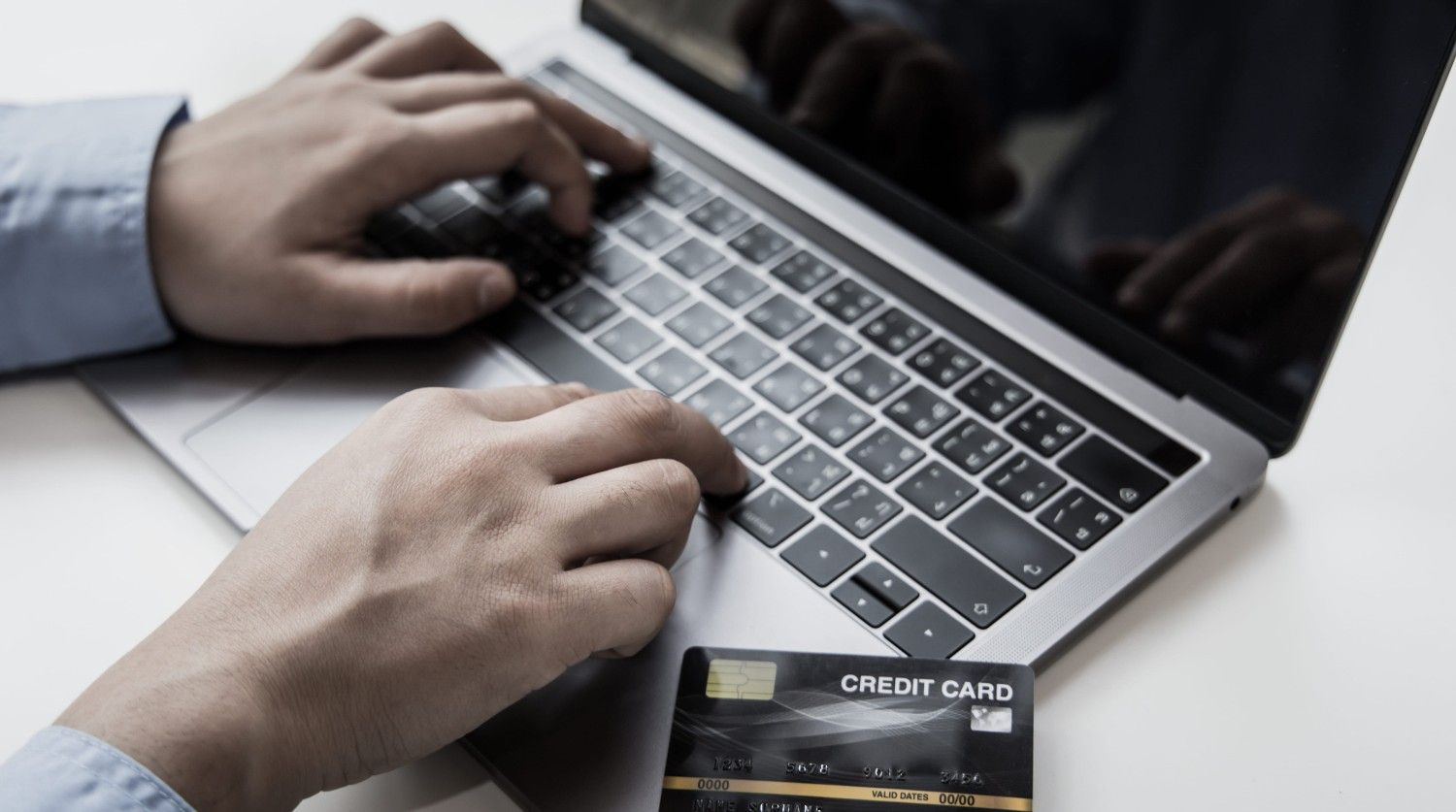 A Man Using A Laptop And A Credit Card To Pay Online