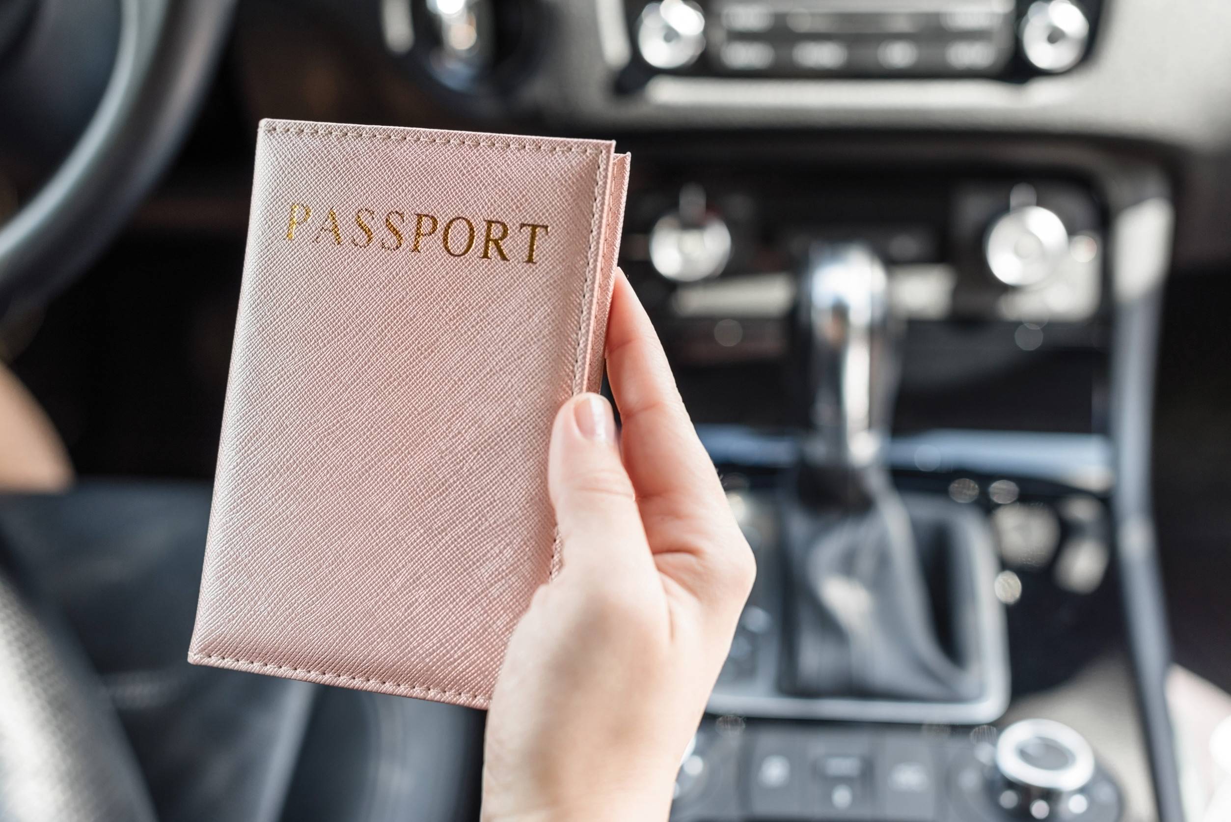 Woman With Passport In Pink Cover Sitting In Car For Customs Check